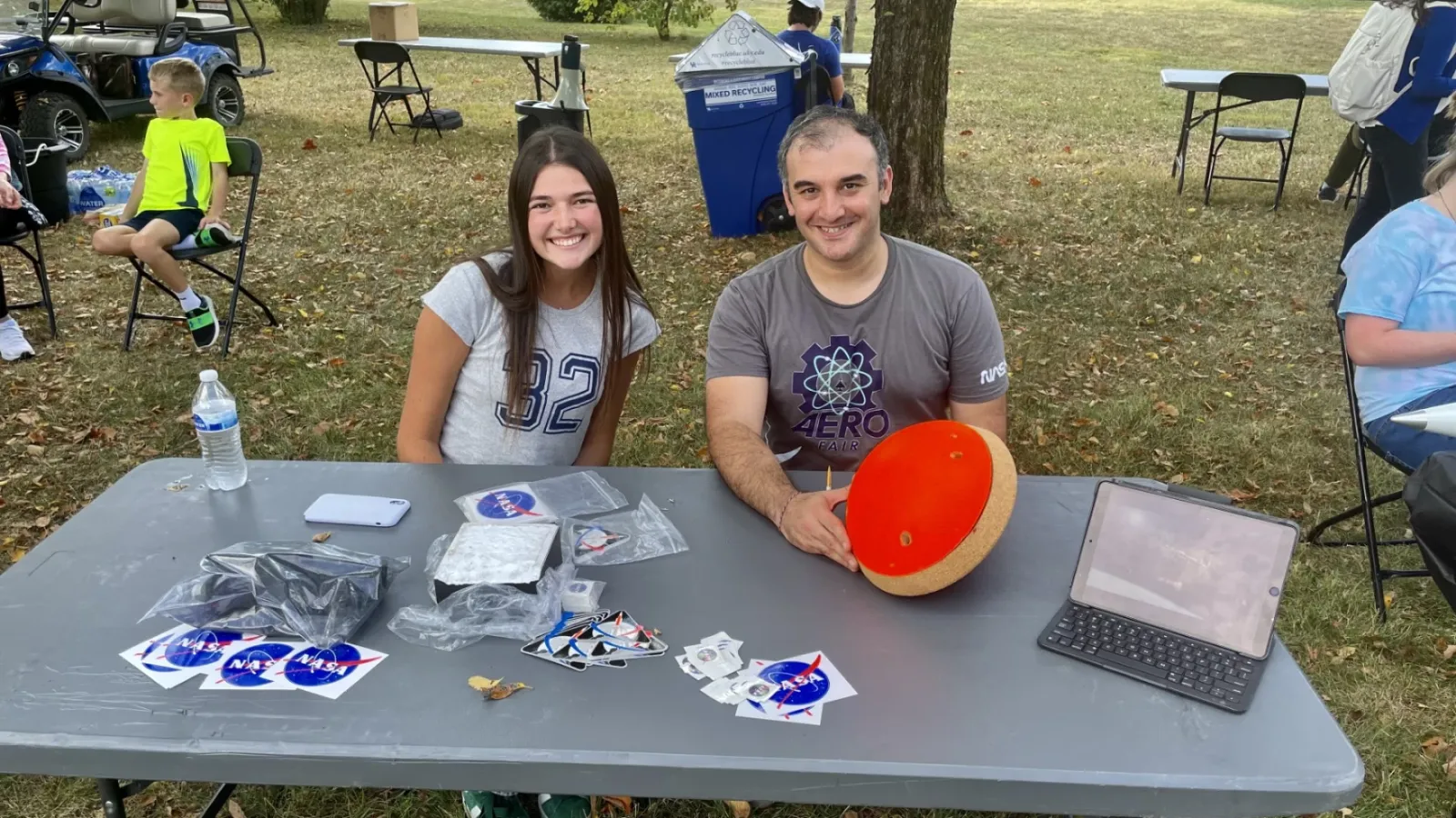 Two students at outdoor event table with NASA materials and displays