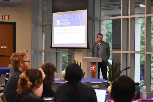 Professor presenting to students in classroom with projector screen